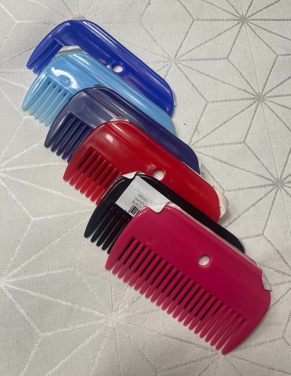 Billede af fem plastikkamme i forskellige farver (pink, sort, rød, mørkeblå og lys blå) lagt i en vandret række på et mønstret stof med geometriske former.