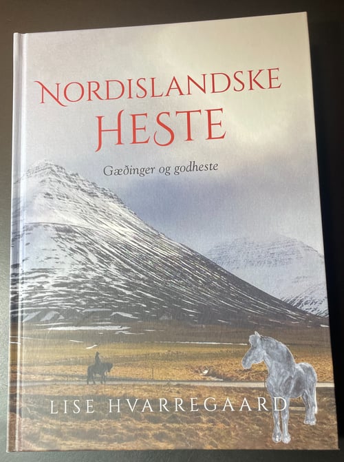 Bogforside med titlen "Nordislandske Heste: Gæðinger og godheste" af Lise Hvarregaard, med et landskab af sneklædte bjerge og en hest i forgrunden. (1)