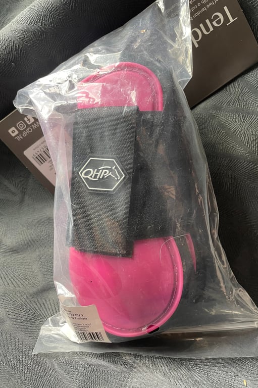 Rosa elastisk beskyttelsesudstyr i gennemsigtig plastpose med sort velcrorem og hvidt logo.