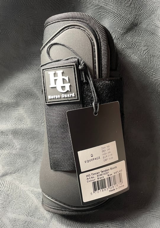 Sort HF Horse Guard hestebeskytter med pris- og produktmærkat, lagt på gråt tekstil.