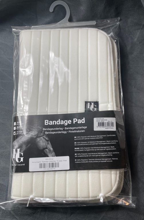 Bandageunderlag i hvidt, quiltet materiale, pakket i gennemsigtig plast med etikette.