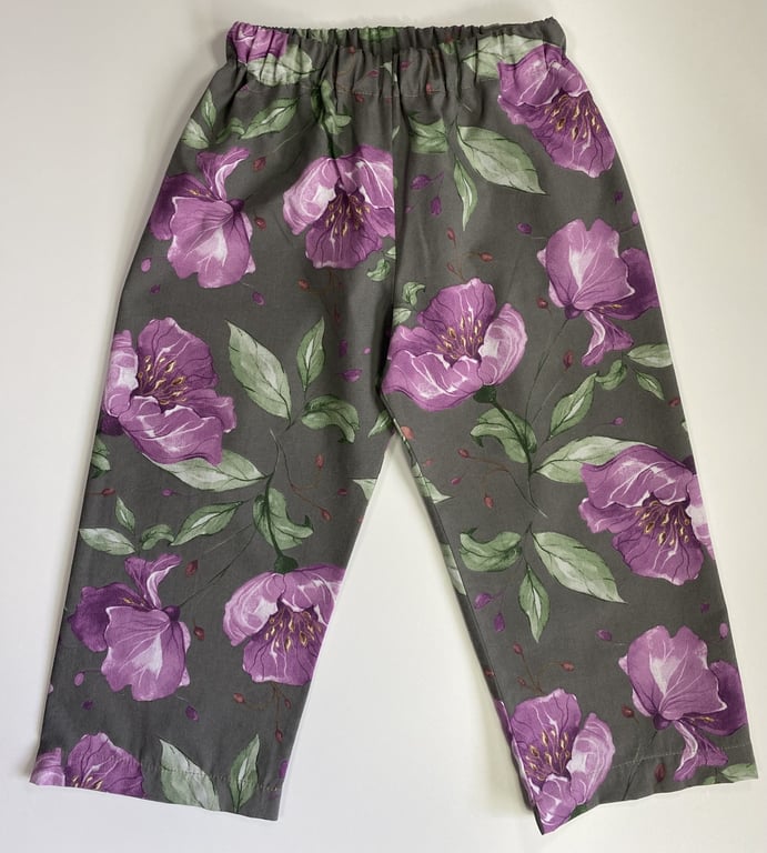 Bukser med elastik i taljen, grå med stort blomsterprint i nuancer af lilla og grønne blade.