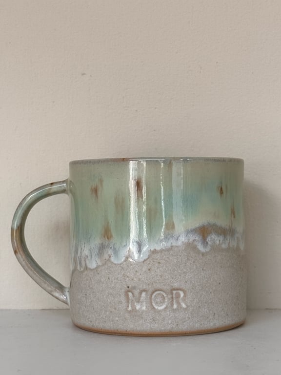 Keramikkrus med grøn og beige glasur og indgraveret teksten "MOR" på forsiden.