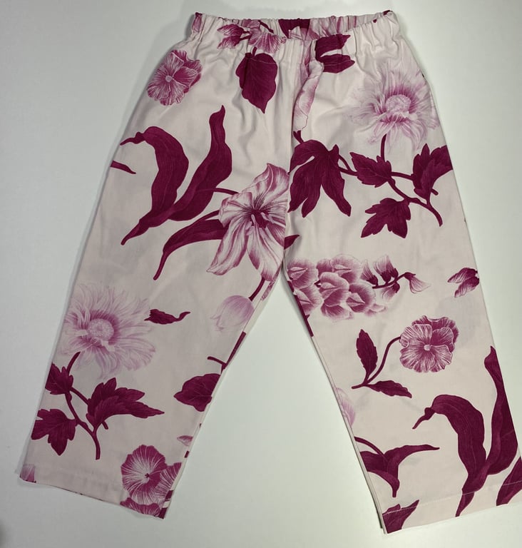 Billede af lyserøde bukser med elastisk talje og mørkerøde blomsterprint.
