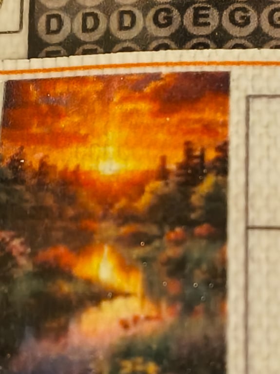 Solnedgang over en skov og en flod, afbildet på et brevkrydsord.