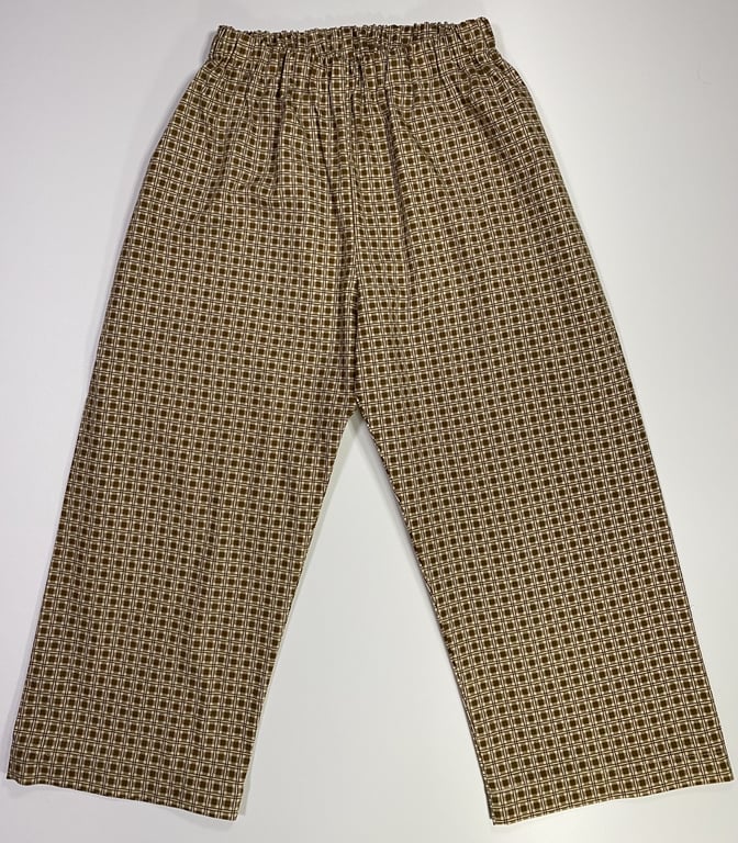 Bukser med elastik i taljen og ternet mønster i beige og brune nuancer, liggende fladt på hvid baggrund.