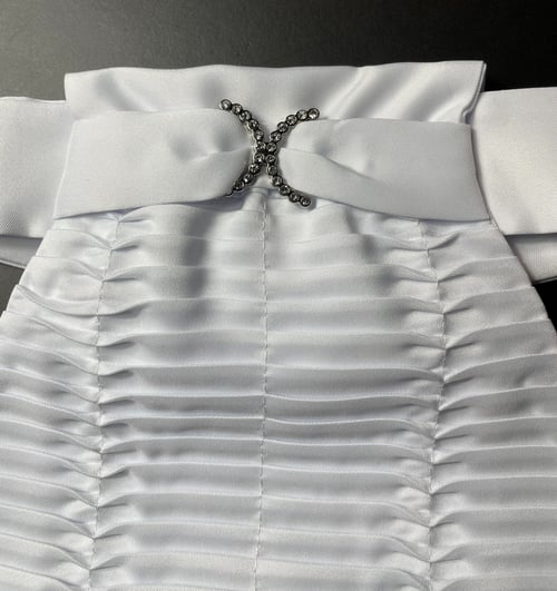Hvid, rynket kjole med bred halskant og dekorativ broche med glitrende sten. (1)