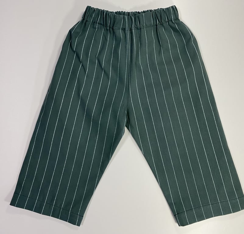 Bukser i mørkegrøn med hvide lodrette striber og elastisk talje, lagt fladt på en hvid overflade.