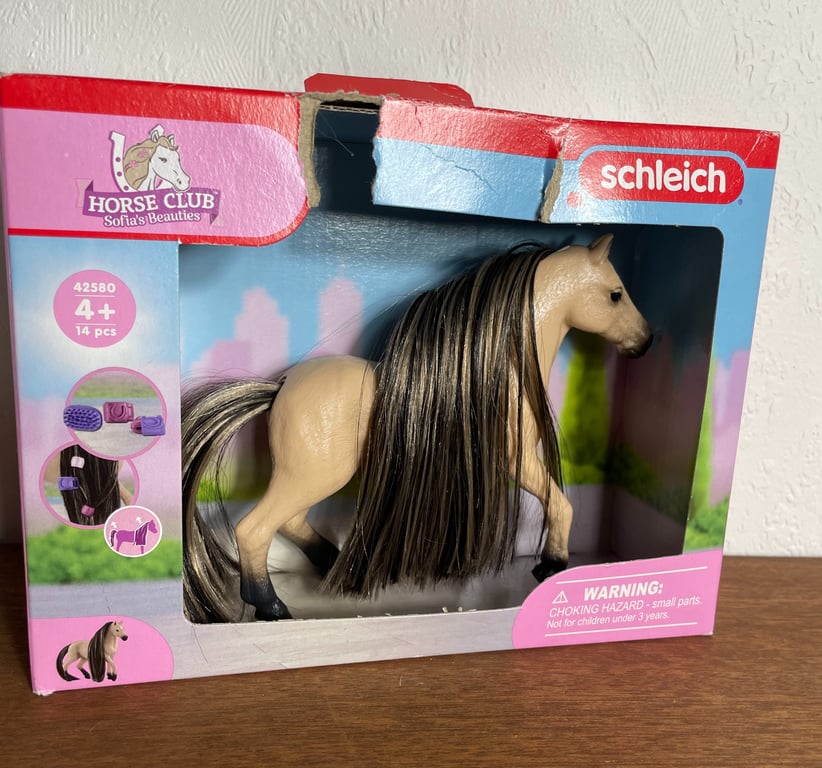 Legetøjsmodel af en beige hest med mørk man og hale i en åbnet Schleich Horse Club æske.