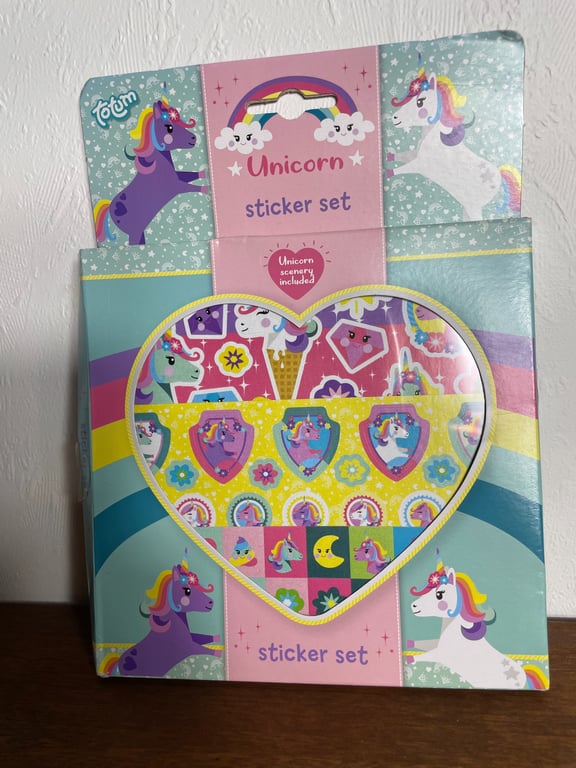 Pakke med farverige unicorn-klistermærker i hjerteformet æske med illustrationer af enhjørninger og regnbuer.