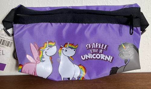 Lilla taske med sort lynlås, pyntet med tegninger af hvide og grå enhjørninger med regnbuefarvede manker og teksten "Sparkle like a unicorn!" (1)