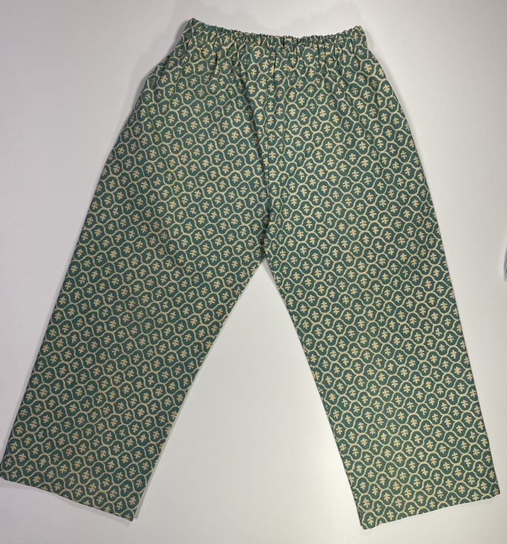 Bukser med elastik i taljen, lavet i stof med grønne og cremefarvede mønstre i geometrisk design.