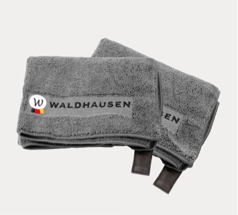 Grå Waldhausen ridesports håndklæder med logo og læderstropper, foldet på hvid baggrund.