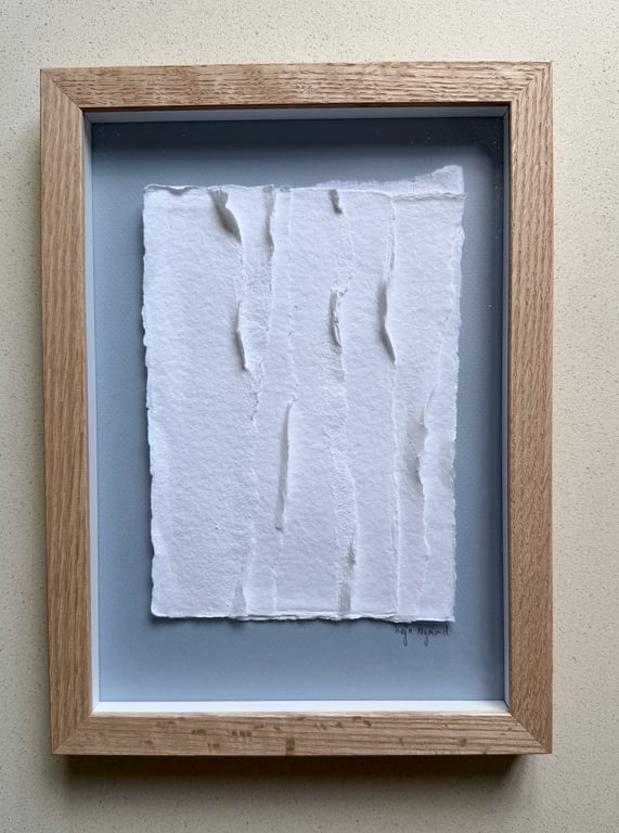 Billedramme med en kunstnerisk opsætning af revet, hvidt papir på en grå baggrund.