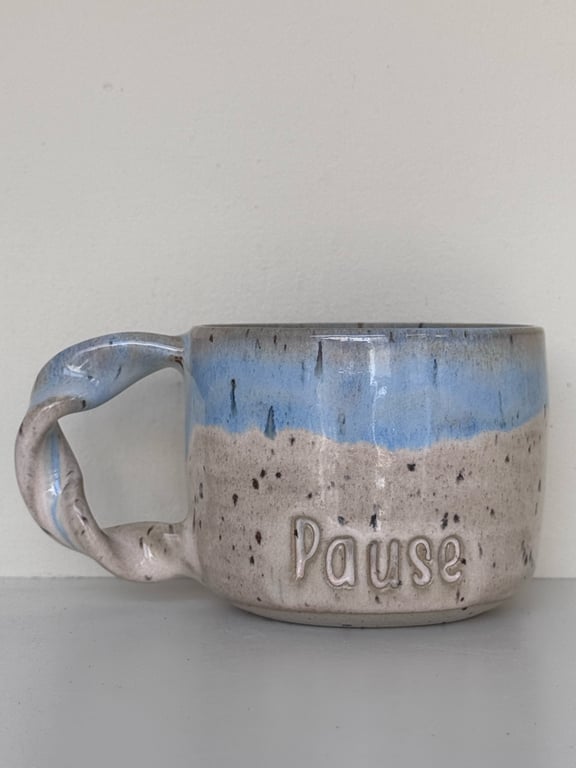 Keramisk kaffekop med blå og beige glasur, hvor ordet "Pause" er indgraveret på siden.
