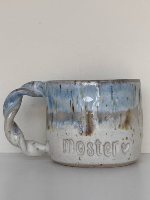 Keramikkrus med blå og beige glasur, snoet hank, og teksten "moster" med et hjerte indgraveret på siden. (1)