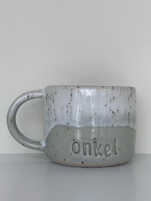 Grå og hvide keramikkrus med teksten "onkel" præget på fronten. (1)