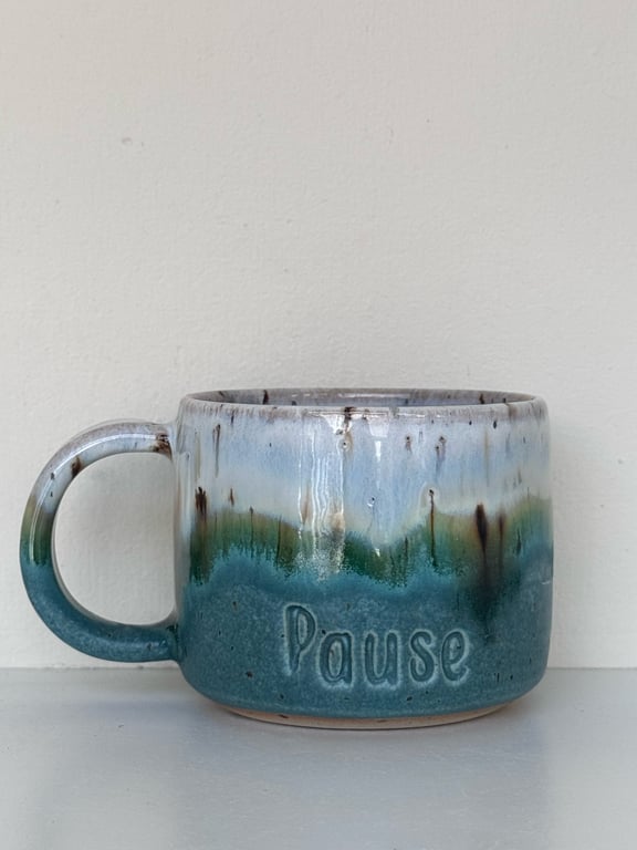 Keramikkrus med blå og grøn glasur og teksten "Pause" præget på siden.