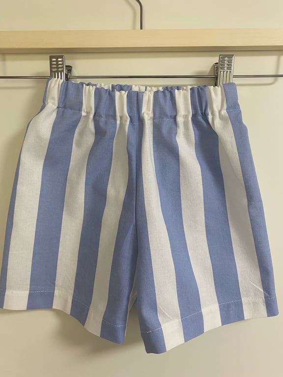 Blå og hvide shorts med lodrette striber hængende på en bøjle.