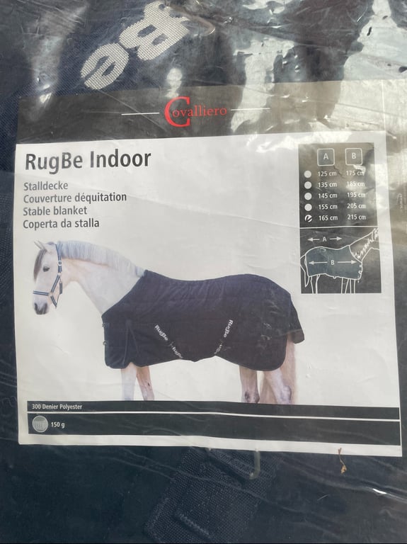 Et produktbillede af en stallagen til heste kaldet "RugBe Indoor" fra mærket Cavalliero med størrelsesguide og billede af en hest iført dækkenet.