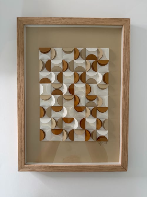 Billedramme med abstrakt geometrisk kunst bestående af gentagne firkanter med halvcirkler i varme jordfarver som brun, beige og hvid. (2)