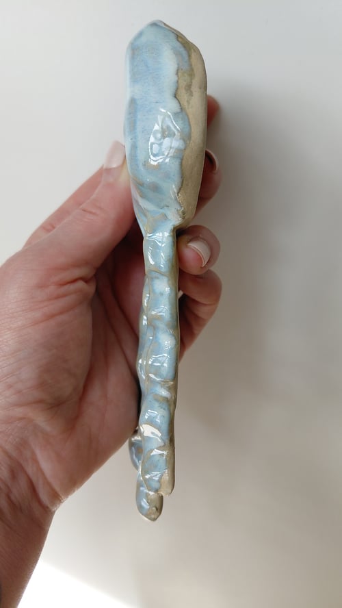 Hånd, der holder en keramisk smørepind med blå og beige glasur. (6)