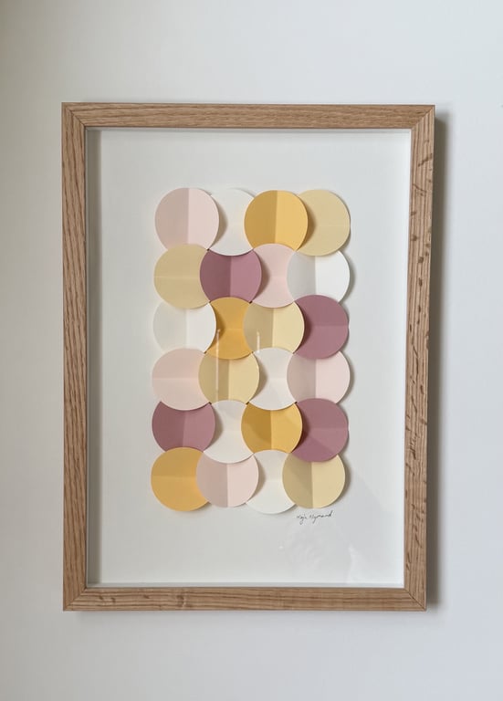 Abstrakt vægkunst i ramme med overlappende cirkler i pastelfarver som gul, lyserød, lilla og hvid.