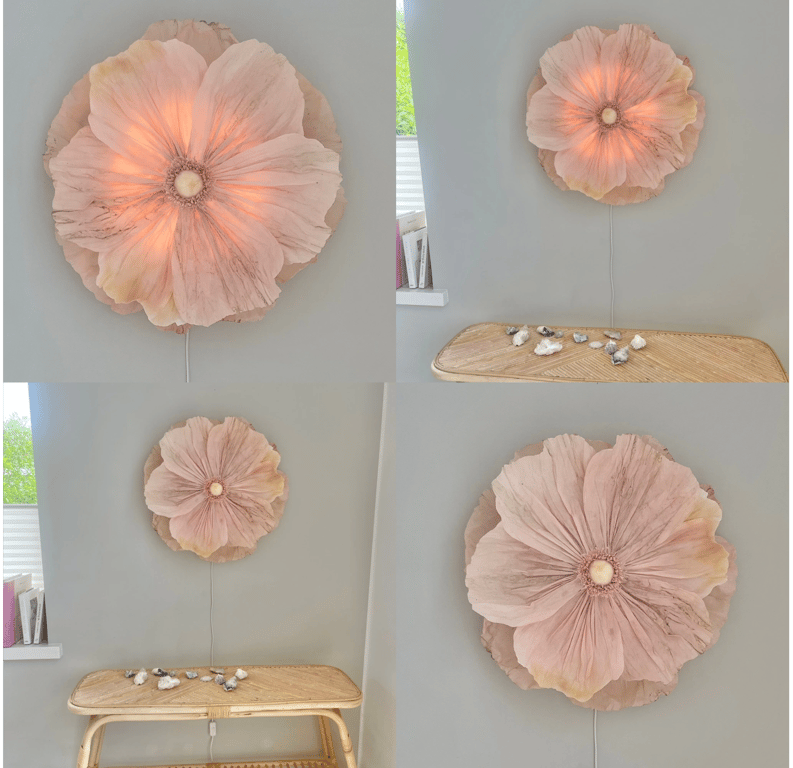 Collage af fire billeder, der viser en væglampe formet som en stor, lyserød blomst monteret på en grå væg over et lyst træs bænk med små dekorative sten.