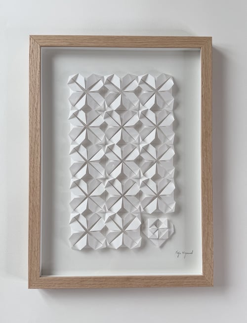 Billedramme med 3D-papirfoldninger arrangeret i et rektangulært mønster, med en underskrift nederst til højre. (1)
