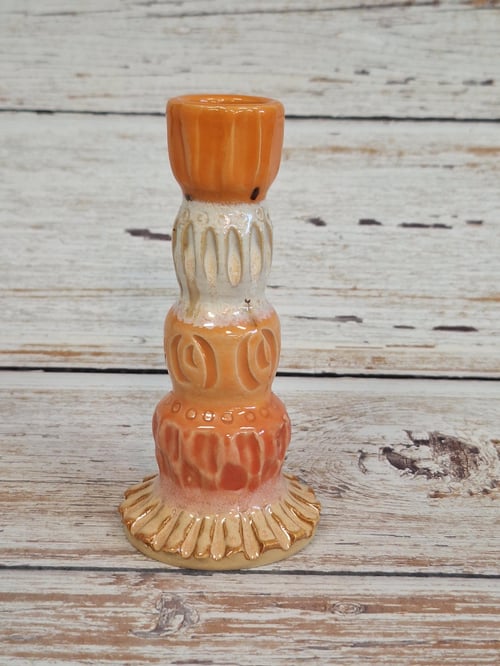 Keramisk lysestage i orange og beige med mønstre, placeret på træbord. (1)