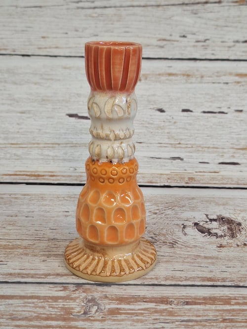 Keramisk lysestage med dekorative mønstre i nuancer af orange, beige og brun. (1)