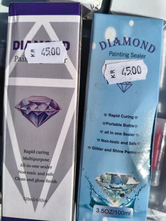 To pakker Diamond Painting Sealer i henholdsvis lilla og blå emballage med prislabels på 45,00 kr.