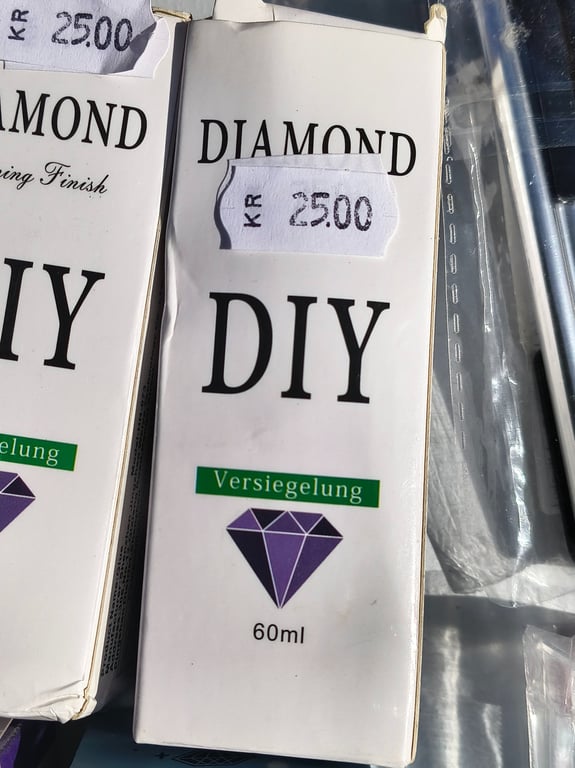 Billede af en hvid emballage med teksten "DIAMOND DIY" og et prisskilt, der viser "KR 25.00". På emballagen står også "Versiegelung" og "60ml" ved siden af en lilla diamantillustration.
