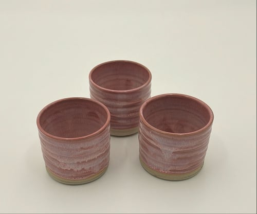 Tre små, runde keramikkrus med en pink og beige glasur på en hvid overflade. (1)