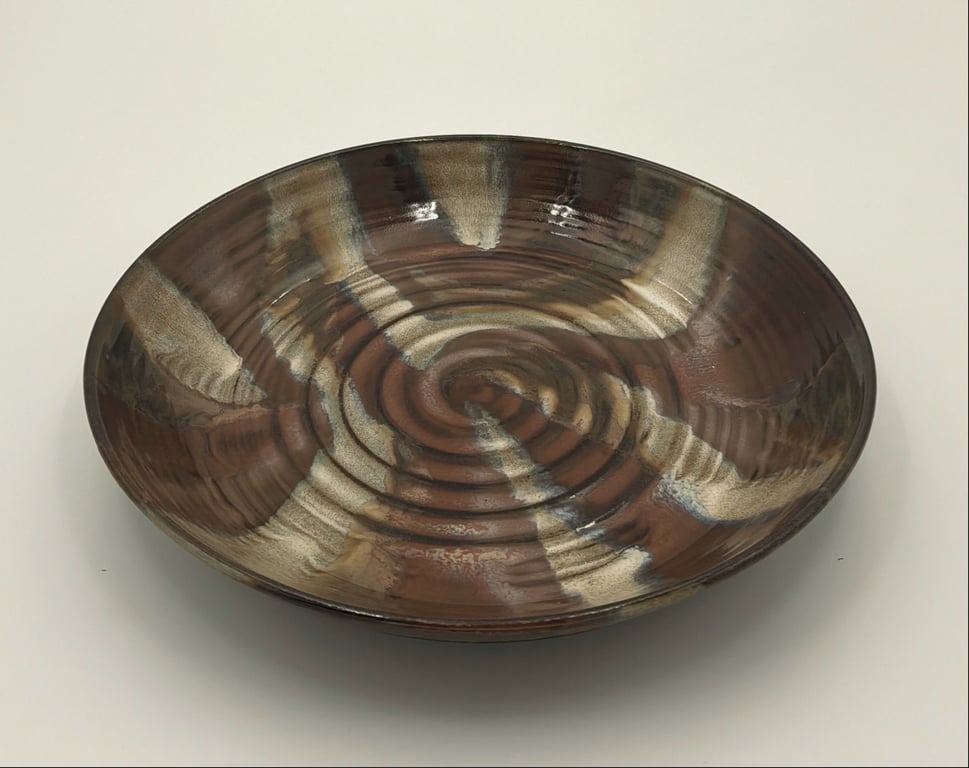 Glaseret keramisk skål med spiralstruktur og mønster i brune, beige og mørke nuancer.