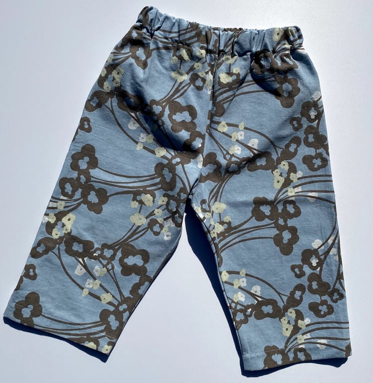 Bukser til baby eller småbørn med elastisk talje, lyseblå med brune og hvide blomsterprint.