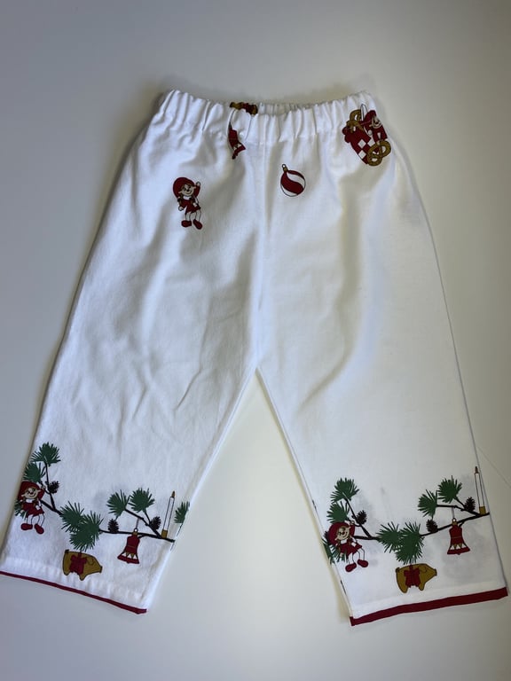 Hvide bukser med juletema, der har tryk af nisser, julekugler, gran og klokker.