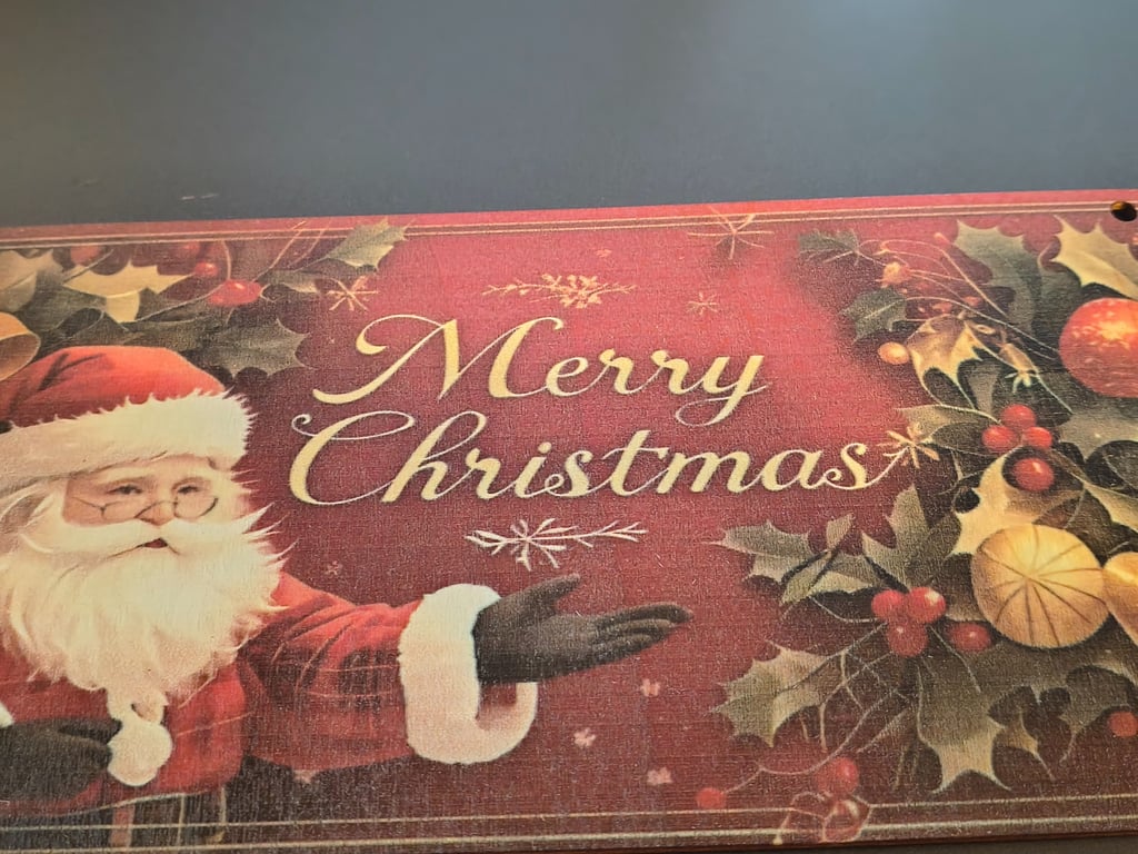 Billede af juleplakat med julemand, juledekorationer og teksten "Merry Christmas" på engelsk.