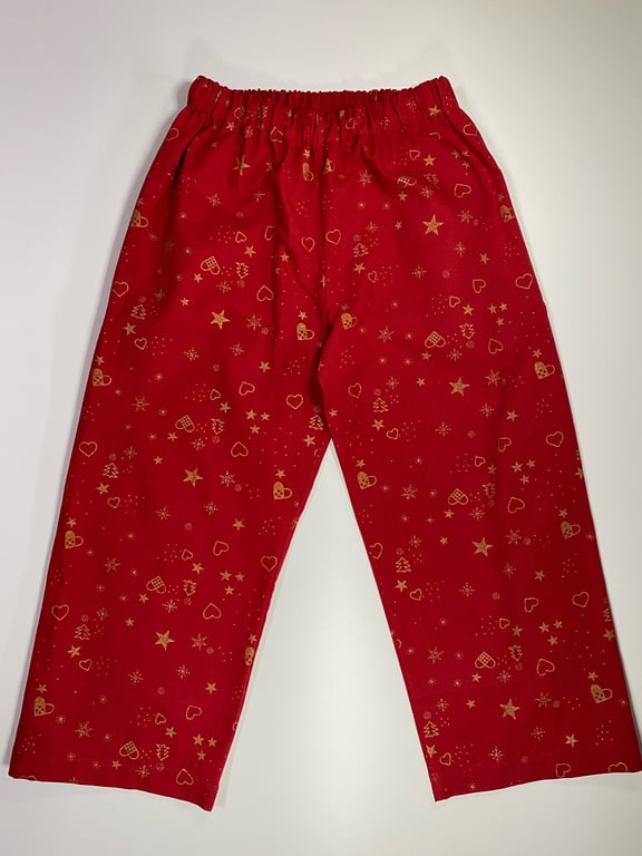 Røde bukser med elastisk talje og guldprint af stjerner, hjerter, julekugler, og små juletræer.