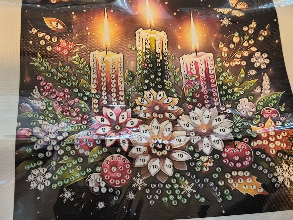 Billede af et maleri efter nummer med tre tændte stearinlys, forskellige blomster og blade, alle mærket med tal til maling.