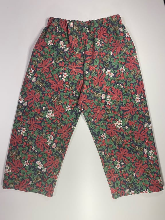 Bukser med elastik i taljen, pyntet med et mønster af grønne blade, røde blomster og hvide blomster.