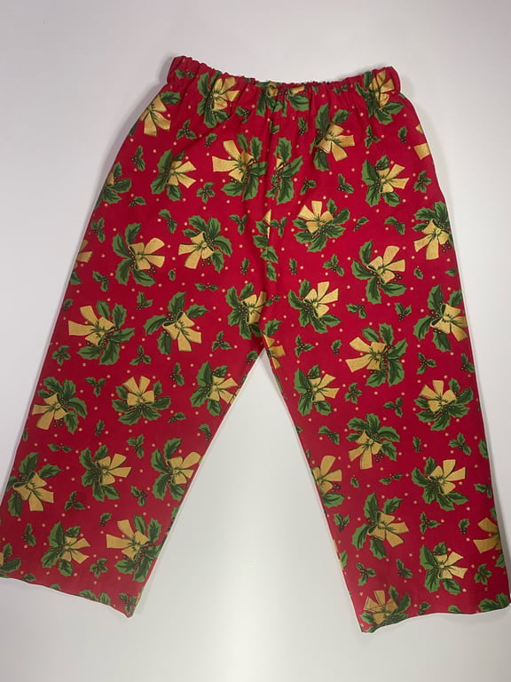 Røde bukser med julemotiver, inklusive gule bånd og grønne kristtornblade.