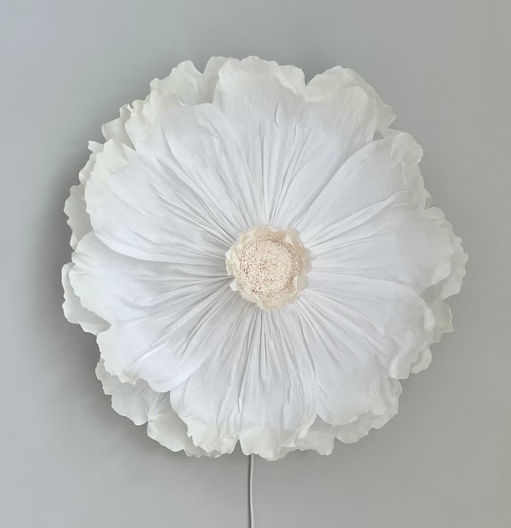 Stor hvid blomsterlampe med bløde kronblade mod en grå baggrund.