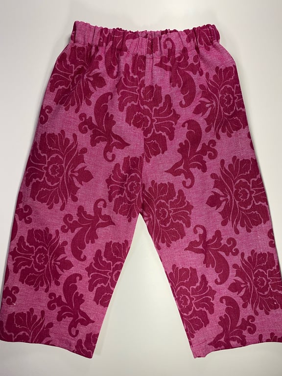 Bukser til børn i pink med mørkerød blomster- og bladmønster, med elastisk talje.