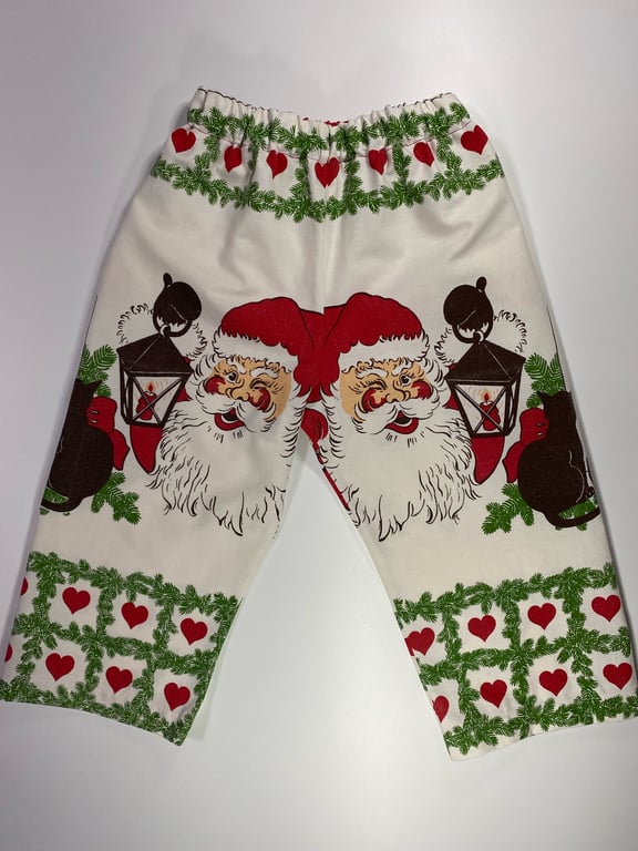 Billede af hvide julesweatpants med tryk af nisse med rød hue, lanterne, grønne grangrene og røde hjerter.