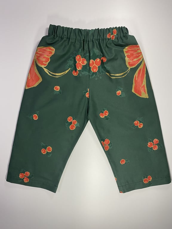 Grønne bukser med elastisk talje og orange blomster- og bærmønster.