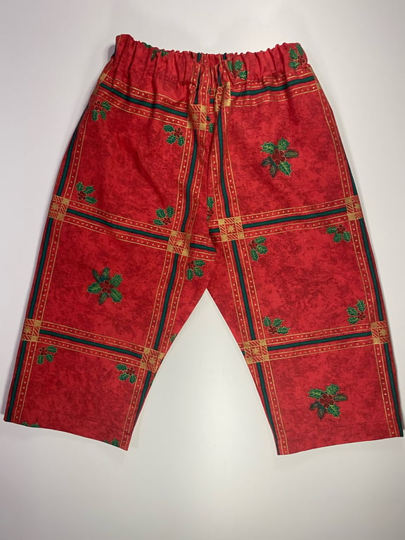 Røde julepyjamasbukser med grønt og gult mønster og elastisk talje.