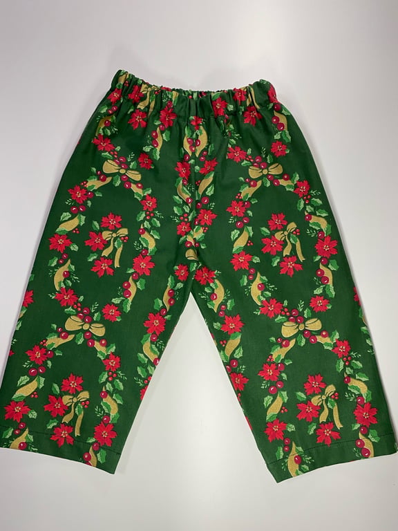 Grønne bukser med elastisk talje og juledekorativt mønster med røde blomster og guldsløjfer.