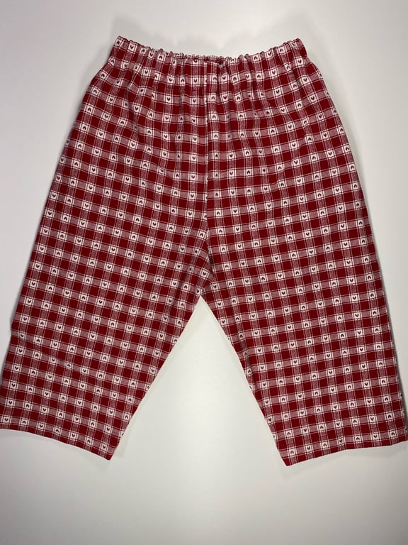 Røde og hvide ternede pyjamasbukser med elastisk talje lagt fladt på hvid baggrund.