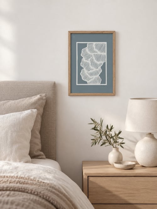 Ny seng med beige sengetøj ved siden af et træ-natbord med en lampe og en vase med grønne grene, samt et abstrakt vægkunst i en træramme. (2)